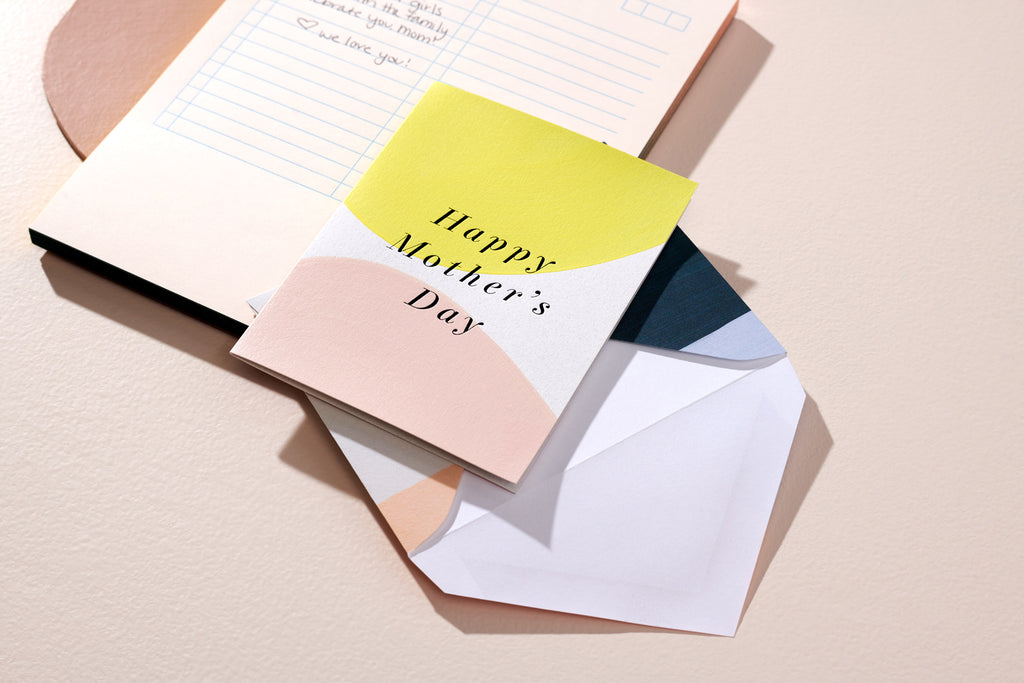 Happy Mother's Day card and envelope sitting on a notebook on beige background