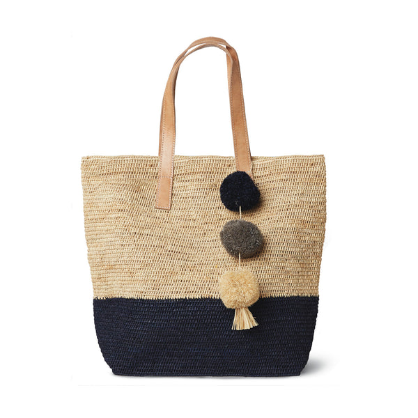 Color block navy colored crocheted carryall with leather straps & raffia pom poms