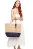 Model holding color block navy colored crocheted carryall with leather straps & raffia pom poms