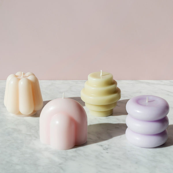 Four sculptural candles: purple, pink, green, and orange