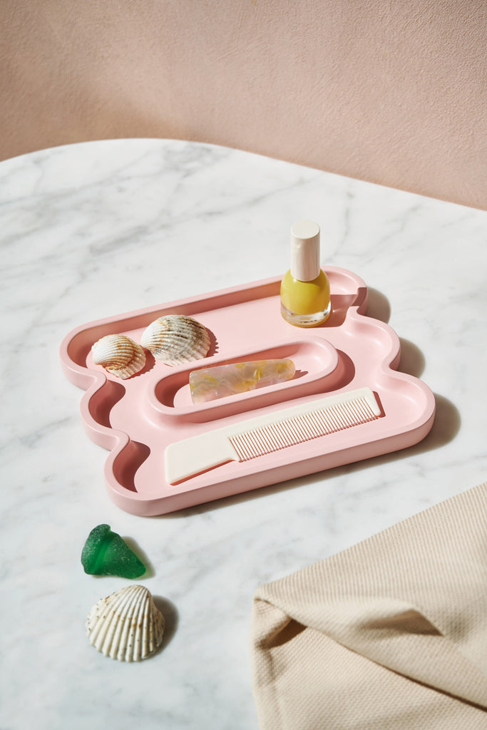 Pink colored catchall tray with props on it
