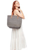 Model holding dove colored crocheted carryall with snap closure, cotton lining & leather straps