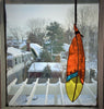 Stained glass feather with red, yellow, and blue panes hanging from leather tie in window