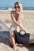 Model sitting on beach holding Serena Navy
