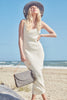 Model in a dress on the beach wearing our Stella raffia sun hat in Dove and our Leah raffia handbag in Dove