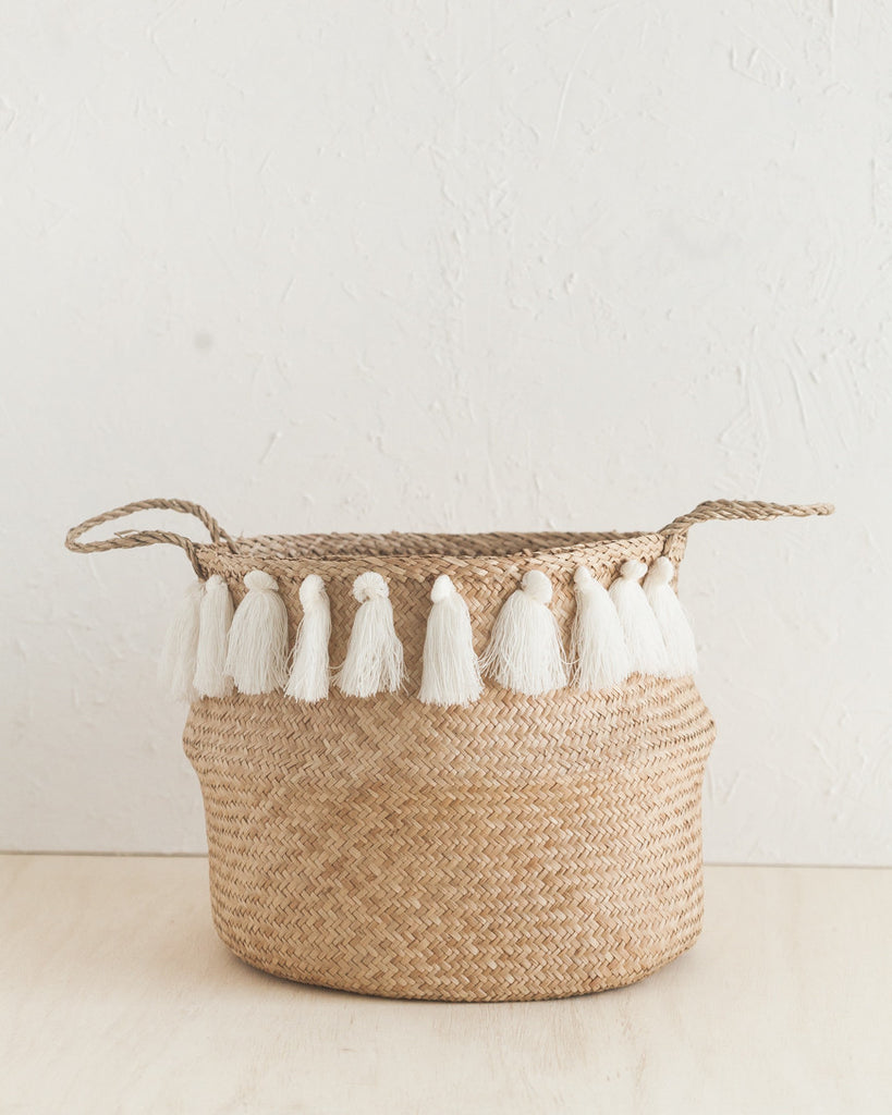 One basket with white tassels on tan background