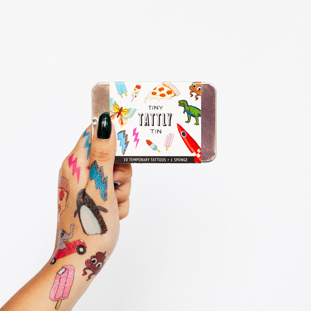 Model hand holding tiny tin of fun tattoos package