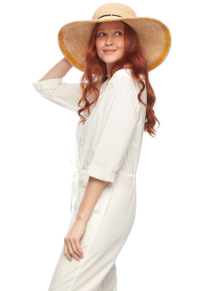 Model wearing crocheted raffia sun hat with leather trim and sunflower colored accent stripe around brim